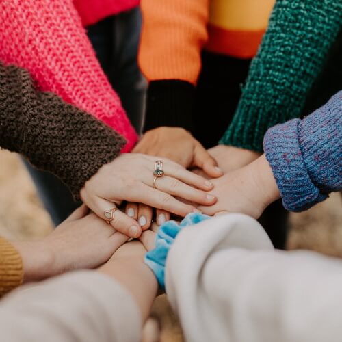 People in a circle placing hands together